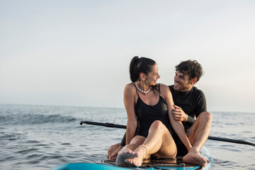 Obraz premium Romantic couple enjoying paddleboarding adventure at sea