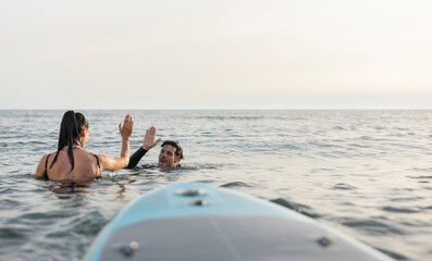 Fototapeta premium Friends celebrating a successful surfing session at sea
