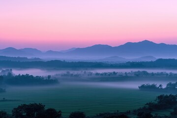 Misty sunrise over layered mountains and rice paddies, creating a serene and colorful landscape.
