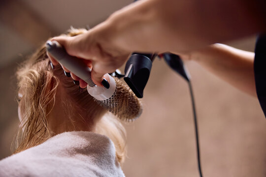 Close up of hairdresser styling woman's hair at salon.