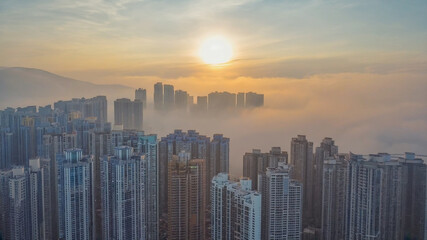Fototapeta premium Urban Enigma: Dense cityscape shrouded in fog illuminated by the morning sun