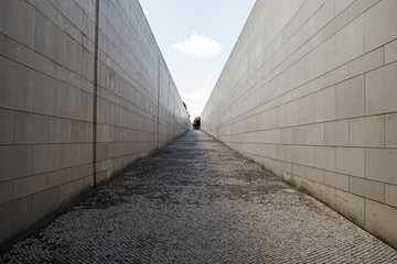 Narrow passageway with tall walls in Fatima, Portugal beneath a clear sky