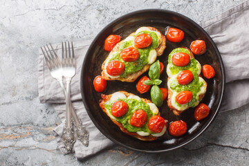 Margherita Chicken is the perfect flavour combo of basil and tomato and is topped with delicious, melty mozzarella cheese close-up on table. Horizontal top view from above