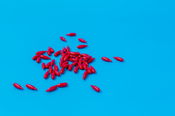 Red Capsules Scattered on Bright Blue Background