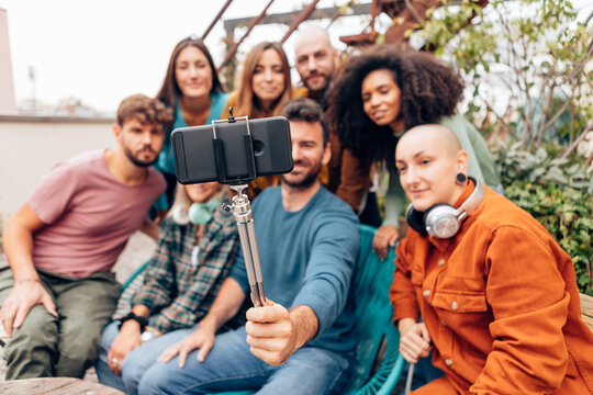 Group of diverse friends taking a selfie on rooftop terrace