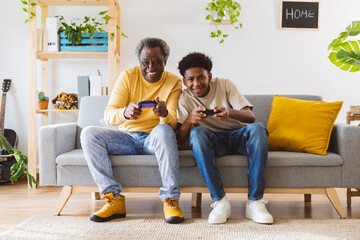 Boy playing video game with grandfather at home