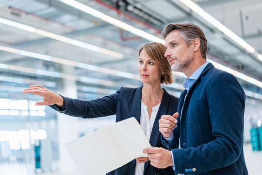 Business professionals discussing plans in a production hall