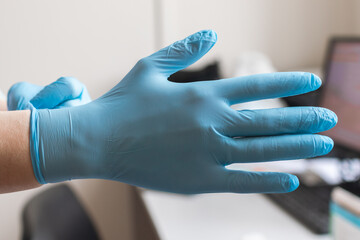 Doctor putting on protective blue gloves