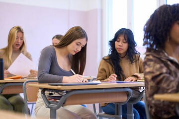 Students taking notes during lesson in classroom at university or college