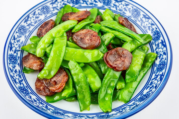 A plate of fried sausage with peas on a white background