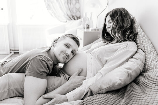 A man hugs a pregnant woman's belly