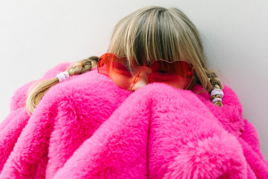 Child in heart sunglasses wrapped in fluffy pink faux fur
