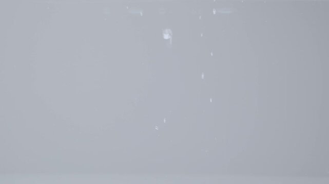 Ice cubes falling into water in slow motion