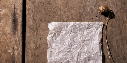 Aged rustic background with empty paper and dry wildflowers. Top view, vintage boho style, space for text
