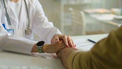 Close up crop of caring female nurse hold hand support patient at consultation in hospital. Doctor...