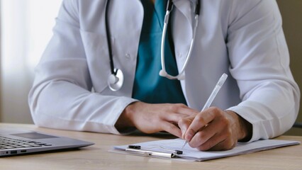 Doctor writing prescription at white table in clinic, closeup.Patient sitting in front of doctor telling his or her condition.