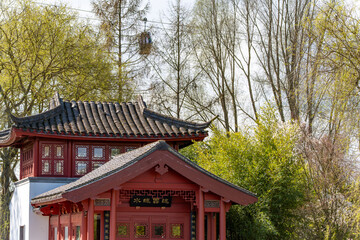 A red building with a red roof and a green tree in front of it. The building has a sign on it that says "The Great Wall"