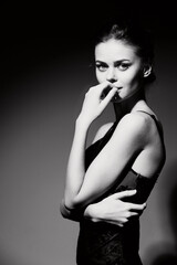 Elegant woman in a black dress posing gracefully against a dark background, exuding confidence and...
