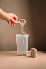 Making protein drink. Pouring chocolate protein powder in a shaker, food supplement concept