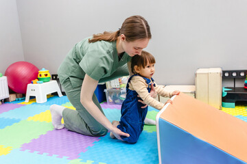 Physical therapist helps a young girl develop her motor skills