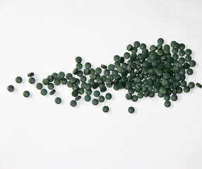 Green Spirulina Tablets Pills Scattered on White Surface
