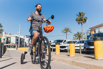 Smiling disabled man riding adaptive bike on sunny urban street - Smiling man with mobility...