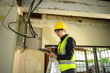 Professional electrician reviewing plans and making notes while conducting an electrical inspection