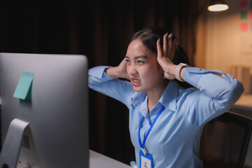 Overworked young businesswoman struggling with a headache while dealing with loud noises from a computer in a dark office, feeling the pressure of looming deadlines and frustration