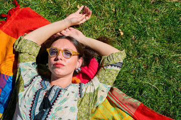 Young woman relaxing on colorful blanket in grass