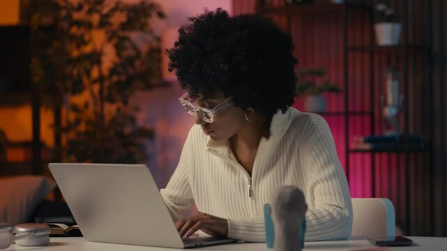 Stylish female graphic designer in eyeglasses working on laptop, writing notes