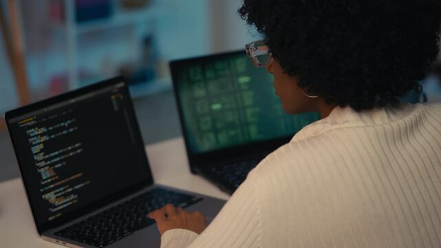 Young female software tester working on laptops in office, checking program bugs