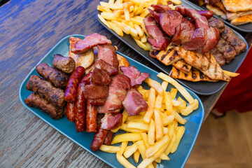Delicious Grilled Meat Platter With Crispy French Fries On Rustic Wooden Table