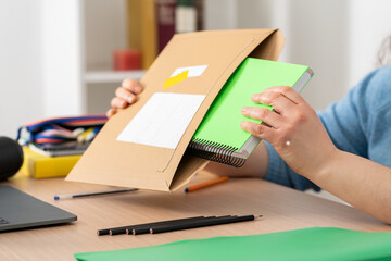 Close up of student woman hands unboxing package delivery with agenda at home