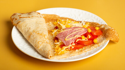 thin pancakes with tomato and cheese filling. serving salty food on yellow background. Thin pancakes with fillings