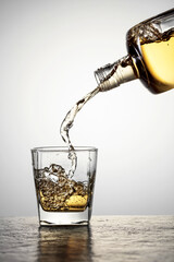 Whiskey is poured from a bottle into a glass.