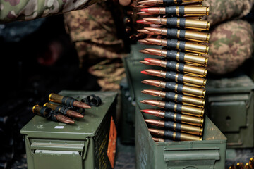 A soldier takes machine gun cartridges out of an ammunition box