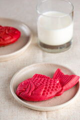 Sweet warm bread in the shape of a crucian carp with banana milk on a table. Poonoppan dessert. Korean food. Vertical orientation.