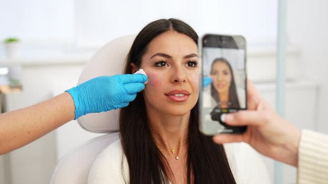 Beautiful and happy young woman sitting on medical chair and looking at the mirror. She is satisfied after successful beauty treatment with hyaluronic acid fillers or botulinum toxin injections.