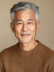 Mature Man Smiling: A portrait of a distinguished senior man with silver hair, wearing a brown sweater, exudes warmth and gentle confidence with a genuine smile.