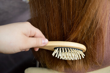 close-up hand brushing long healthy hair wooden hairbrush sustainable beauty eco-conscious grooming tools zero-waste haircare plastic-free alternatives routines eco-friendly self-care natural material