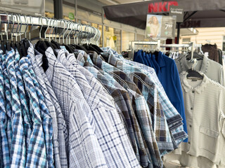 Assorted plaid and solid men's shirts on outdoor clothing rack display