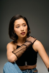 Fototapeta premium Stylish young woman relaxes with confidence in a modern urban studio backdrop