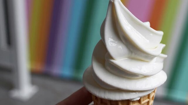 Colorful Ice Cream Cone Against Vibrant Rainbow Striped Background

