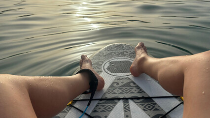 Person relaxing on paddle board enjoying sunset on water surface