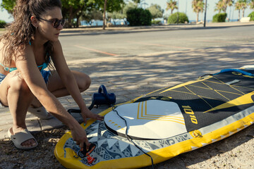 Woman inflating paddle board on the beach getting ready for stand up paddling