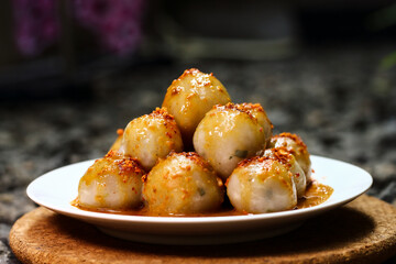 Cilok is a traditional food from Indonesia, made from tapioca, round shape, chewy textured. White plate on the gray gravel. Selective focus