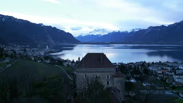Aerial: Chatelard Castle, Montreux, Dents du Midi and Lake Geneva at sunset in canton of Vaud, Switzerland, push in drone shot