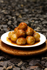 Cilok is a traditional food from Indonesia, made from tapioca, round shape, chewy textured. White plate on the gray gravel. Selective focus