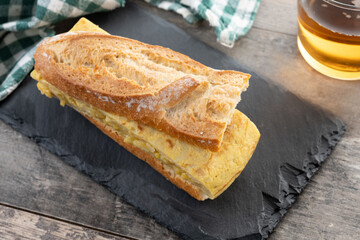 Spanish potato omelette sandwich on wooden table. Bocadillo de tortilla