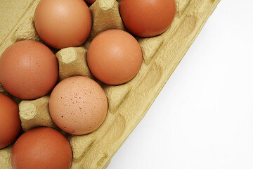 Top view of raw rustic brown eggs in a green paper box. Space for text.